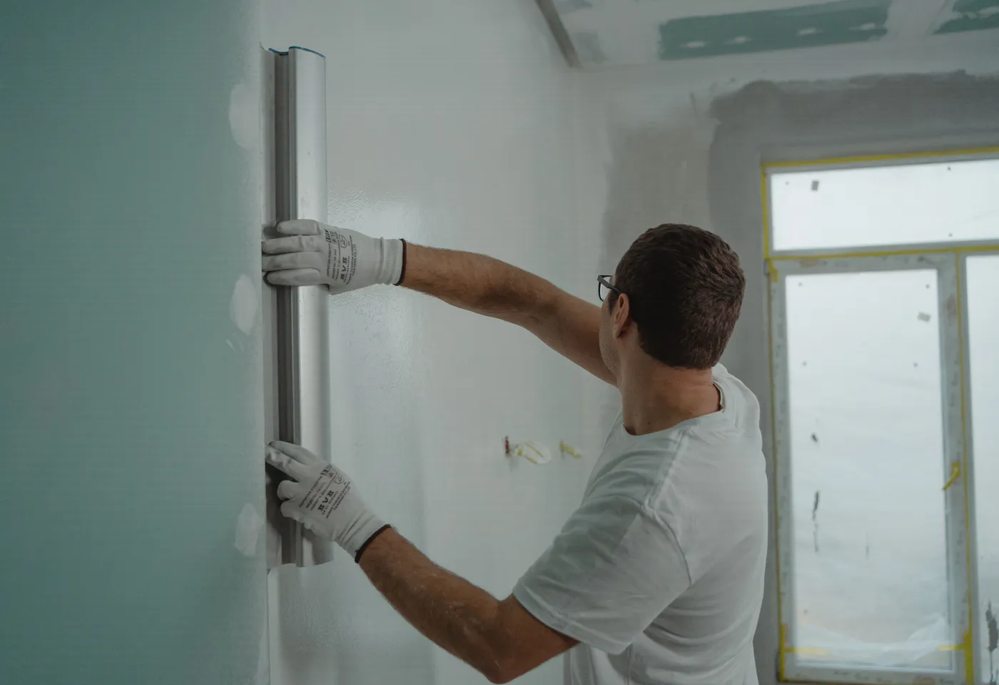 Poseur contrôlant l’alignement d’un ouvrage intérieur